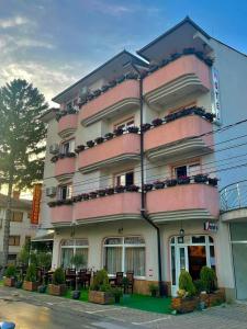 a pink building with tables and chairs in front of it at Hotel Montenegro in Struga