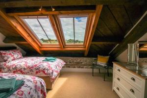 a attic bedroom with two beds and a window at The Old Carriage Works in Lostwithiel