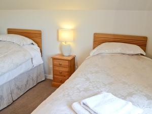 a bedroom with two beds and a lamp on a night stand at Druim-nan-deur in Lochcarron