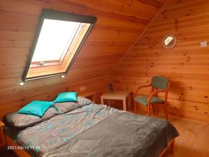 Dormitorio con cama y ventana en una cabaña de madera en Wakacyjne Zacisze, en Rusinowo