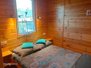 Un dormitorio con una cama con almohadas azules y una ventana en Wakacyjne Zacisze, en Rusinowo