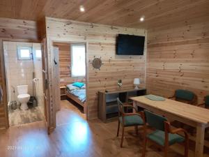 Habitación con pared de madera, mesa y cama. en Wakacyjne Zacisze, en Rusinowo