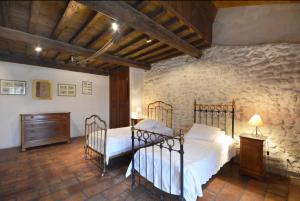 a bedroom with two beds and a stone wall at Charmante maison en Camargue avec piscine partagée in Saintes-Maries-de-la-Mer +12 photos