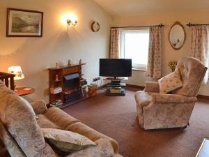 sala de estar con sofá, sillas y TV en Dyke Heads Stable, en Gunnerside