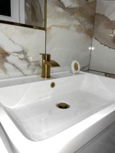 a white sink with a gold faucet in a bathroom at terfyn hall holiday apartment 3 stargazer in Prestatyn +30 photos