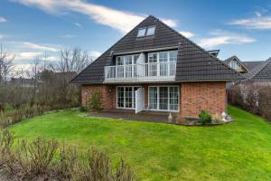 a red brick house with a large yard at Haus-Deichsfenne-App-3-OG in Sankt Peter-Ording