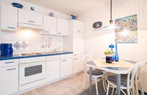 kuchnia z białymi szafkami i stołem z krzesłami w obiekcie Haus-Frisia-Appartement-402 w mieście Sankt Peter-Ording
