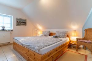 a bedroom with a wooden bed and a chair at FeWo-Salzwiesen in Süderhöft