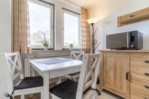 a kitchen with a table and chairs and a tv at Haus Südergeest - Appartement Lio in Tating