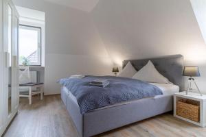 a bedroom with a large bed with a blue blanket at Haus Südergeest - Appartement Lio in Tating