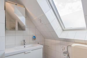 ein weißes Bad mit einem Waschbecken und einem Fenster in der Unterkunft Haus Angela - Appartement Tom in Sankt Peter-Ording