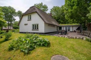 a white house with a thatched roof and a patio at HYGGE-unter-Reet in Westerhever