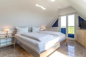 a white bedroom with a large bed and a tv at Haus-Eriel-OG-links in Brösum