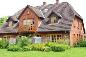 una gran casa de ladrillo con terraza en un patio en Hohe-Duene en Vollerwiek