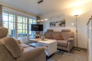 uma sala de estar com um sofá e uma televisão em Haus-Deichsfenne-App-2-Suenneck-EG em Sankt Peter-Ording