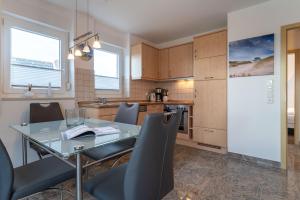 Una cocina y un comedor con una mesa de cristal y sillas. en Haus-Eriel-OG-rechts, en Brösum