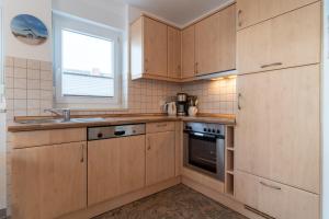 a kitchen with wooden cabinets and a window at Haus-Eriel-OG-rechts in Brösum +21 photos