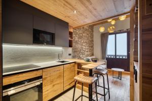 een keuken met houten kasten en barkrukken bij Appartement 123 (RDP) in Tignes