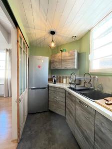 a kitchen with wooden cabinets and a stainless steel refrigerator at Very bright nest with terrace in the village in La Flotte