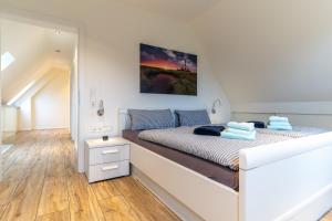 a white bedroom with a bed and a mirror at Wohnung-Windboee in Sankt Peter-Ording