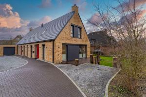 a brick house with a driveway in front of it at Wohnung-Windboee in Sankt Peter-Ording