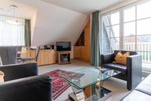 uma sala de estar com um sofá e uma mesa de vidro em Haus-Deichsfenne-App-4-OG em Sankt Peter-Ording