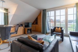 uma sala de estar com mobiliário e uma grande janela em Haus-Deichsfenne-App-4-OG em Sankt Peter-Ording