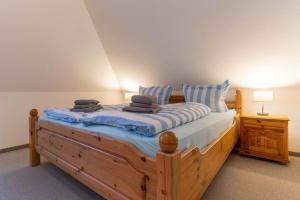 um quarto com uma cama de madeira e 2 almofadas em Haus-Deichsfenne-App-4-OG em Sankt Peter-Ording