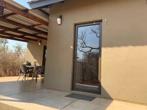 a door to a patio with a table and a window at African Olive in Hoedspruit