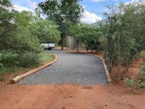 a driveway with trees and a truck in the distance at African Olive in Hoedspruit +1 photo