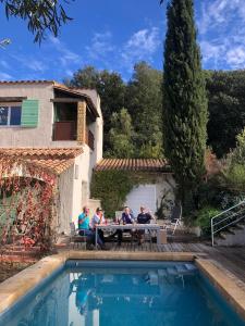 un grupo de personas sentadas en una mesa junto a una piscina en Villa Bonheur Vallespir en Céret