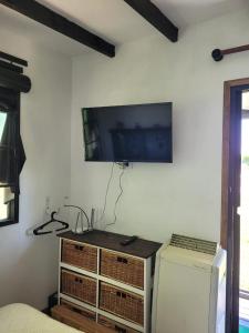 Habitación con TV en la pared y nevera. en Cabaña los coronillos en San Clemente del Tuyú
