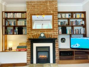 a living room with a fireplace and a tv at Angel Cottage in Halesworth