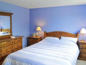 a blue bedroom with a large bed and a mirror at Angel Cottage in Halesworth