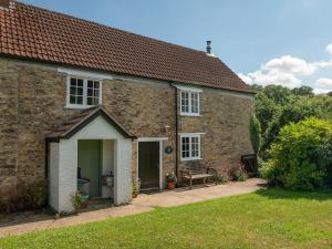 una casa de ladrillo con un banco en un patio en Old Orchard Cottage, en Haydon