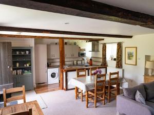 cocina y sala de estar con mesa y sillas en Old Orchard Cottage, en Haydon