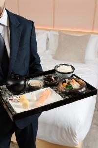 a man in a suit holding a tray of food at The Prince Akatoki London in London