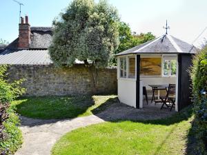 een tuinhuisje met een tafel en stoelen in de tuin bij Swiss Cottage in Chideock