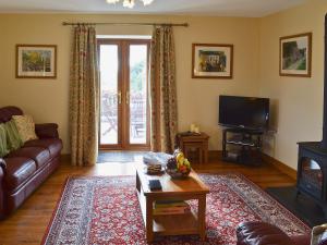 a living room with a couch and a tv at Helygen in Talybont