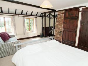 a bedroom with a large white bed and a chair at Field Cottage in Sudbourne