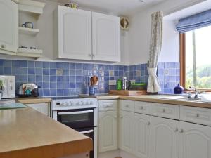 a kitchen with white cabinets and blue tiles at Hope Cottage in Knighton