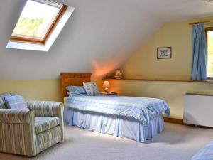 a bedroom with a bed and a chair in a attic at Hope Cottage in Knighton
