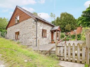 una casa de piedra con una valla de madera delante de ella en Hope Cottage, en Knighton