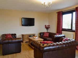 a living room with leather furniture and a flat screen tv at Firth View in Garmouth