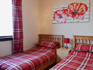 two beds in a bedroom with red flowers on the wall at Firth View in Garmouth
