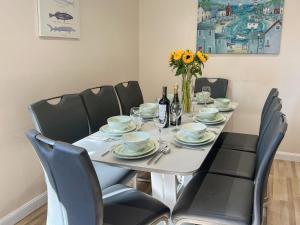 a dining room table with chairs and a white table with flowers at Firth View in Garmouth