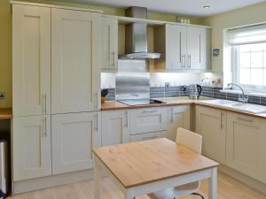 a kitchen with white cabinets and a wooden table at North Shore in Crantock