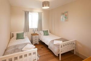 two twin beds in a room with a window at The Dairy in Cricklade