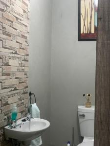 baño con lavabo blanco y pared de ladrillo en Jobe Guesthouse, en Pietermaritzburg