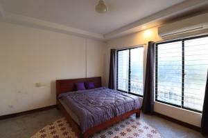 ein Schlafzimmer mit einem Bett und zwei großen Fenstern in der Unterkunft Theary apartment in Phumĭ Ta Phŭl